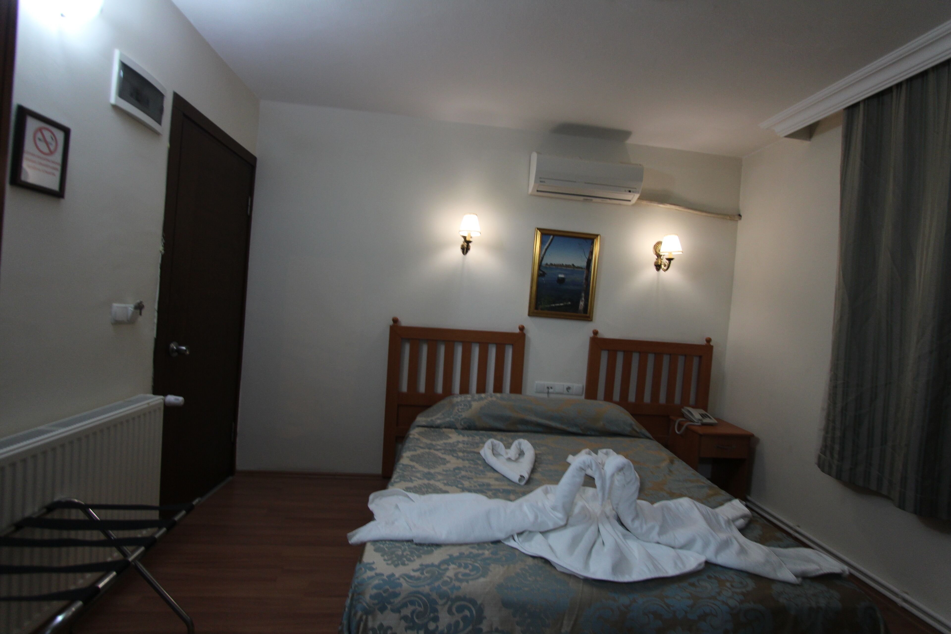 Ein Hotelzimmer mit Bett, Holz-Kopfteil, Nachttisch und Wandlampe.
