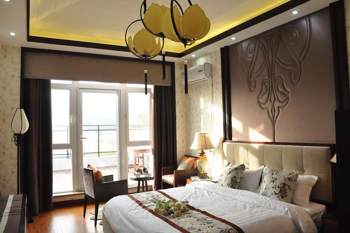 Une chambre d’hôtel avec un lit, une chaise, une table, un piano et une grande fenêtre.
