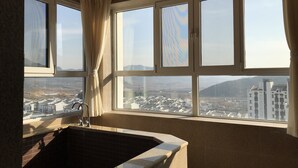 Ein Badezimmer mit einer Badewanne, einem Waschbecken und einem Fenster mit Vorhängen.