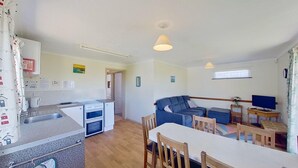 Un espacio habitable compacto con kitchenette, zona de comedor y sala de estar con sofá y sillas.