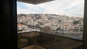 Vista desde un balcón sobre una zona urbana densamente poblada, con numerosos edificios y una calle con automóviles.