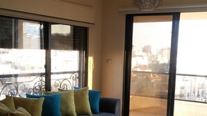 Una sala de estar con un sofá seccional, una mesa de centro y vistas de la ciudad a través de amplios ventanales.