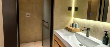 A modern bathroom with a large mirror, a sink, and a shower area.