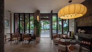 A spacious indoor area with tables and chairs, a large potted plant, and a hanging light fixture. - Yangshuo Riverview Hotel (Guilin)