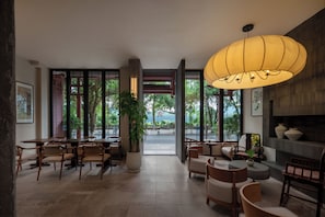 A spacious indoor area with tables and chairs, a large potted plant, and a hanging light fixture. - Yangshuo Riverview Hotel (Guilin)