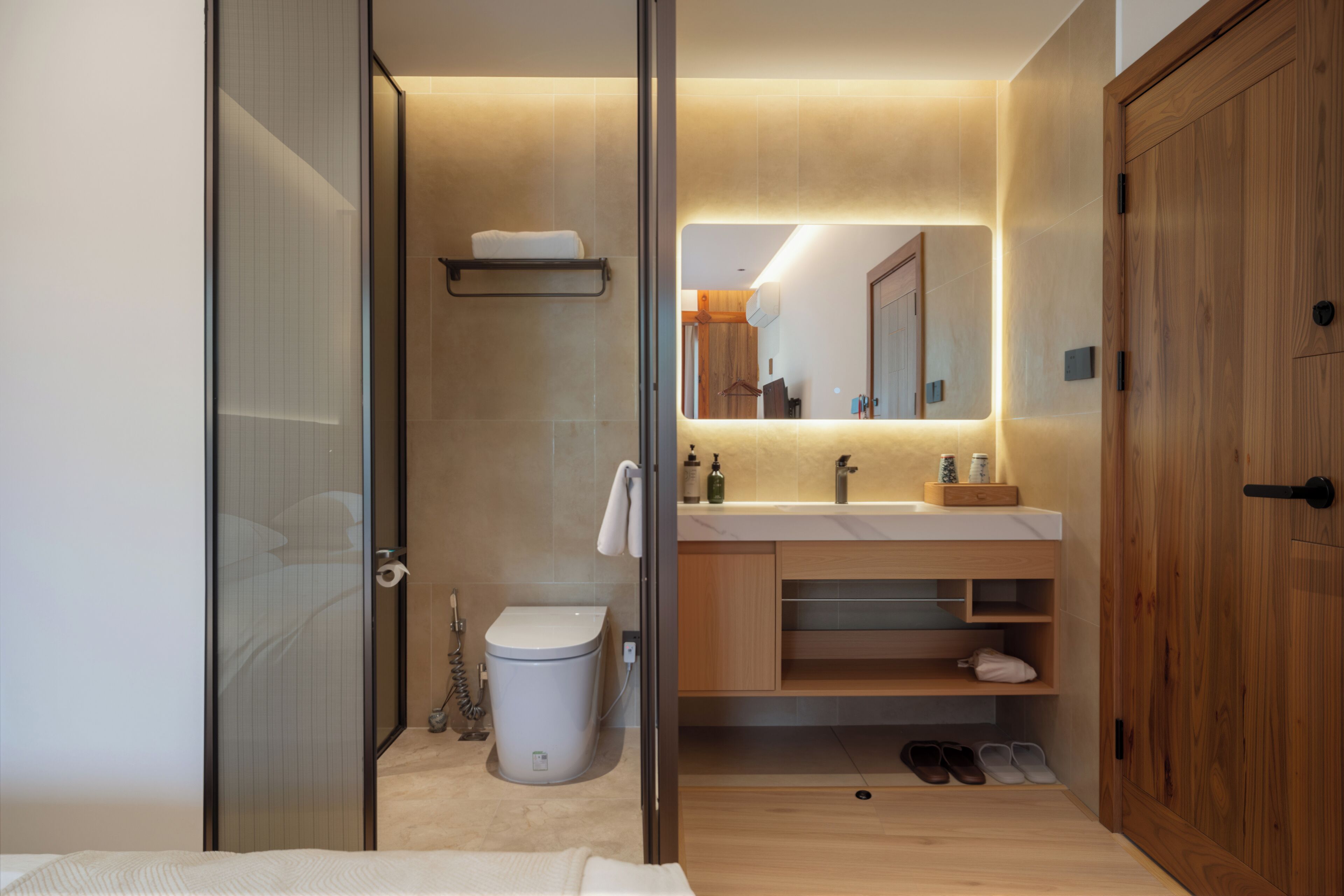 Ein modernes Badezimmer mit Duschkabine aus Glas, Toilette, Waschbecken mit Spiegel und Holzschrank.