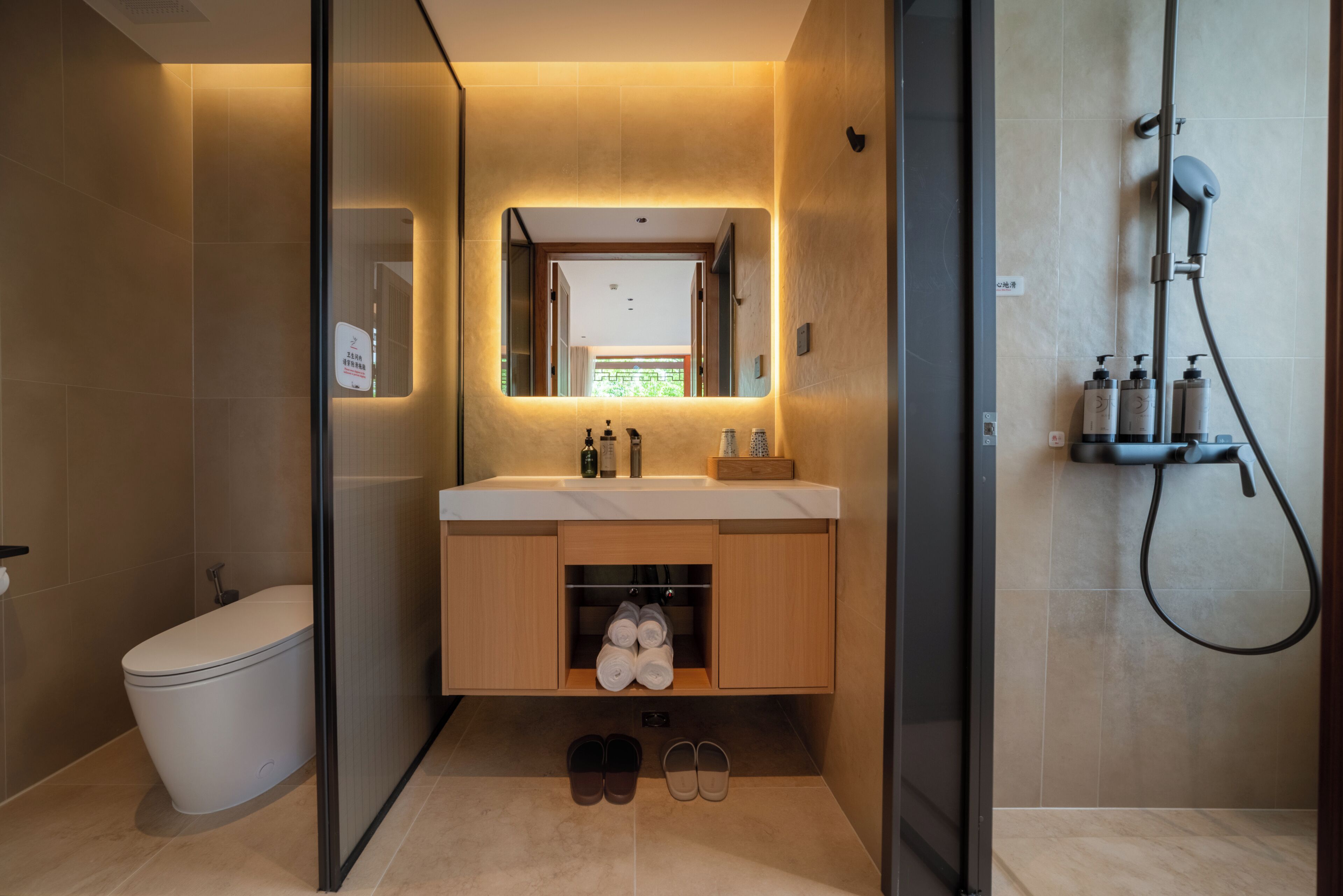 A modern bathroom with a toilet, a sink with a mirror, a shower, and a shoe rack.