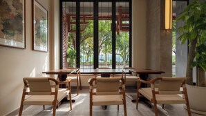 A dining area with a large table and chairs, framed artwork on the wall, and a view through a window. - Yangshuo Riverview Hotel (Guilin)