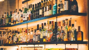 Een bar met meerdere planken vol diverse flessen drank.