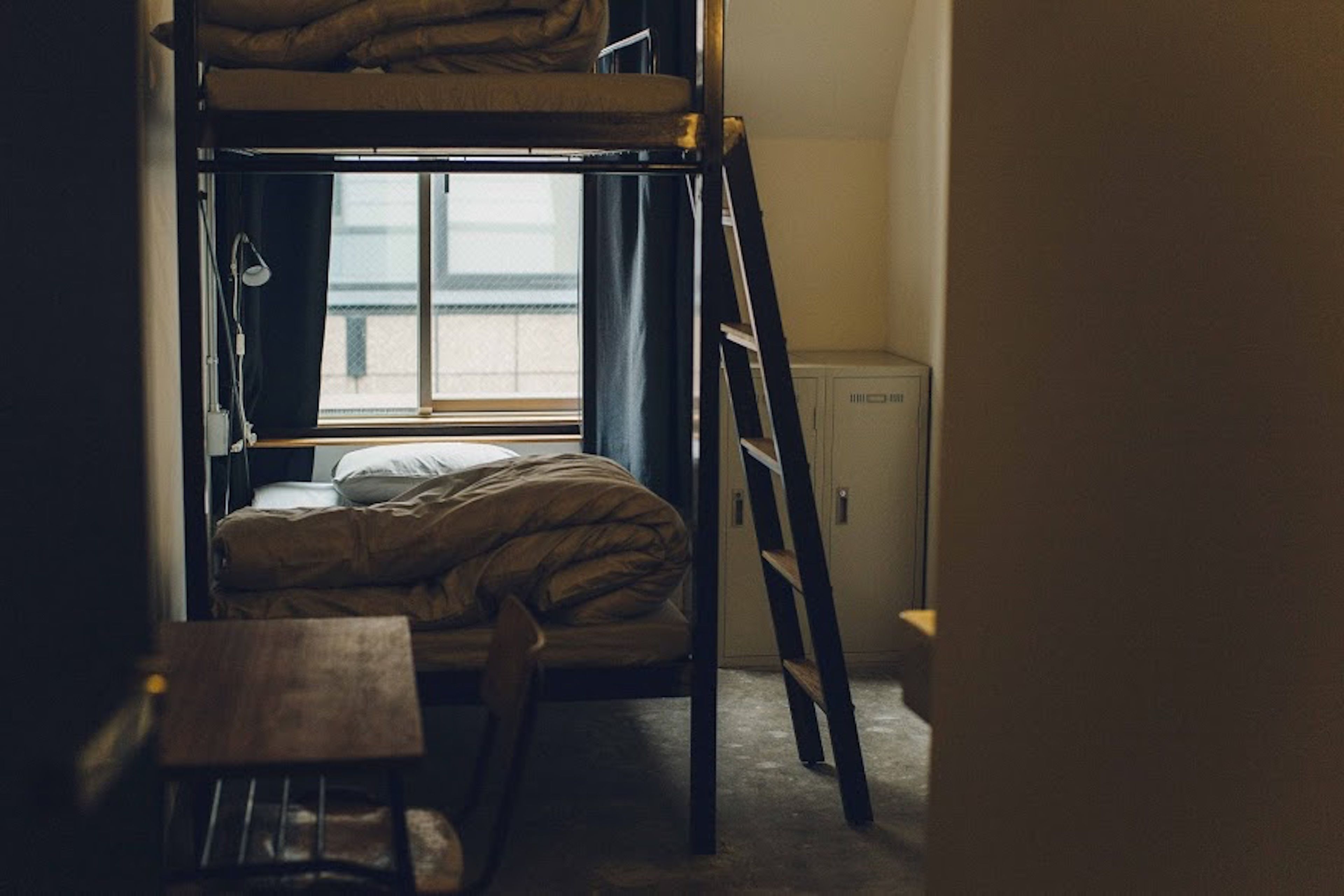 A bunk bed room with a window, a desk, and a cabinet.