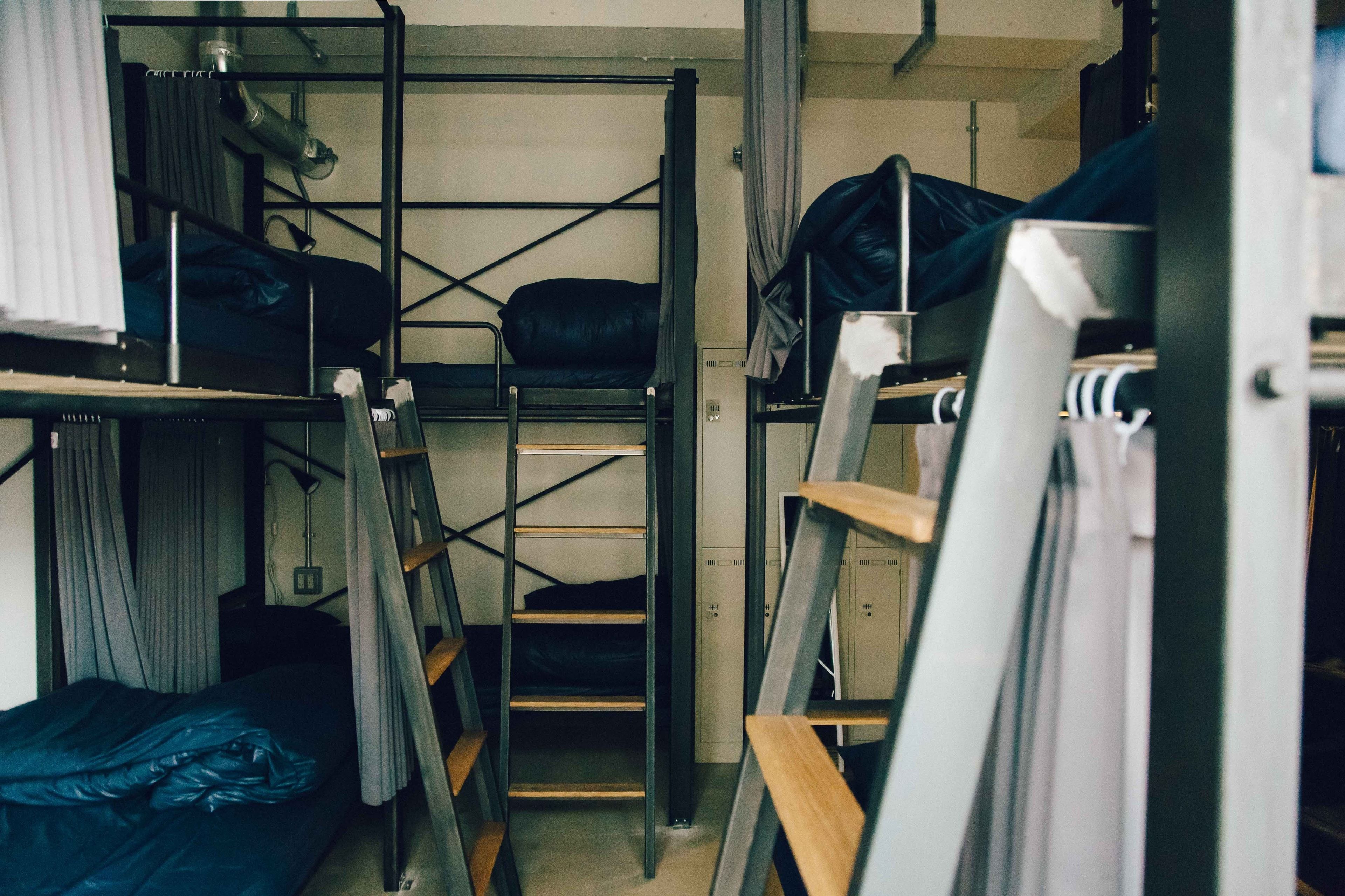 A dormitory room with bunk beds, a ladder, and a desk.