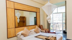 A hotel room with a large bed, a wooden headboard, a large mirror, and a balcony with a view. - Kigaliview Hotel & Apartaments (Kigali)