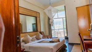 A hotel room with a bed, a desk, and a chair. There is a large window and a door visible. - Kigaliview Hotel & Apartaments (Kigali)