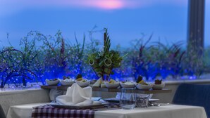 Ein Esszimmertisch ist gedeckt mit Tellern, Schüsseln und Besteck, mit Blick auf blauen Himmel und Pflanzen im Hintergrund.