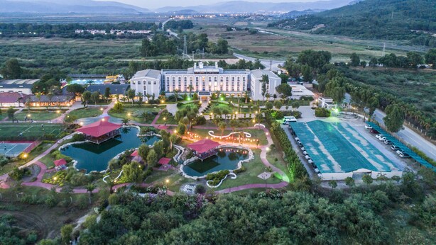 Eine Vogelperspektive eines großen Resorts mit mehreren Swimmingpools, angelegten Gärten und einem mehrstöckigen, imposanten Gebäude.