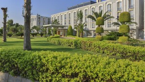 Ein großes, elegantes Hotel mit einer symmetrischen Fassade, gepflegten Gärten und ordentlich geschnittenen Formschnitten.