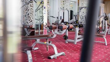 A gym with various exercise machines, a red patterned floor, and decorative wall panels.