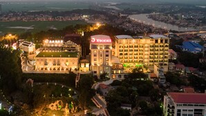 A hotel complex with multiple buildings, including a prominent Phoenix hotel. The complex features a landscaped garden area with pathways and a small pond. - Phoenix Resort Bac Ninh (Vu Ninh)