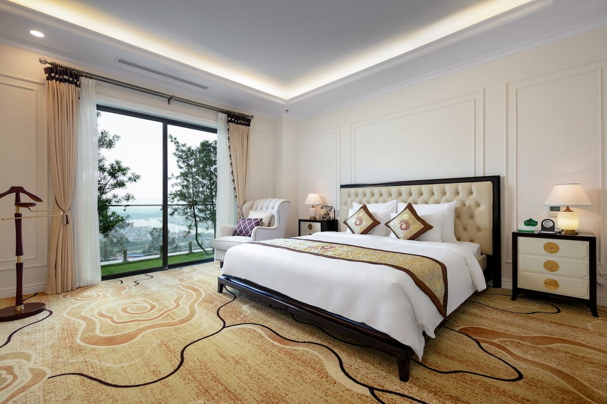 A spacious bedroom with a large bed, a view of greenery outside, and a modern design.
