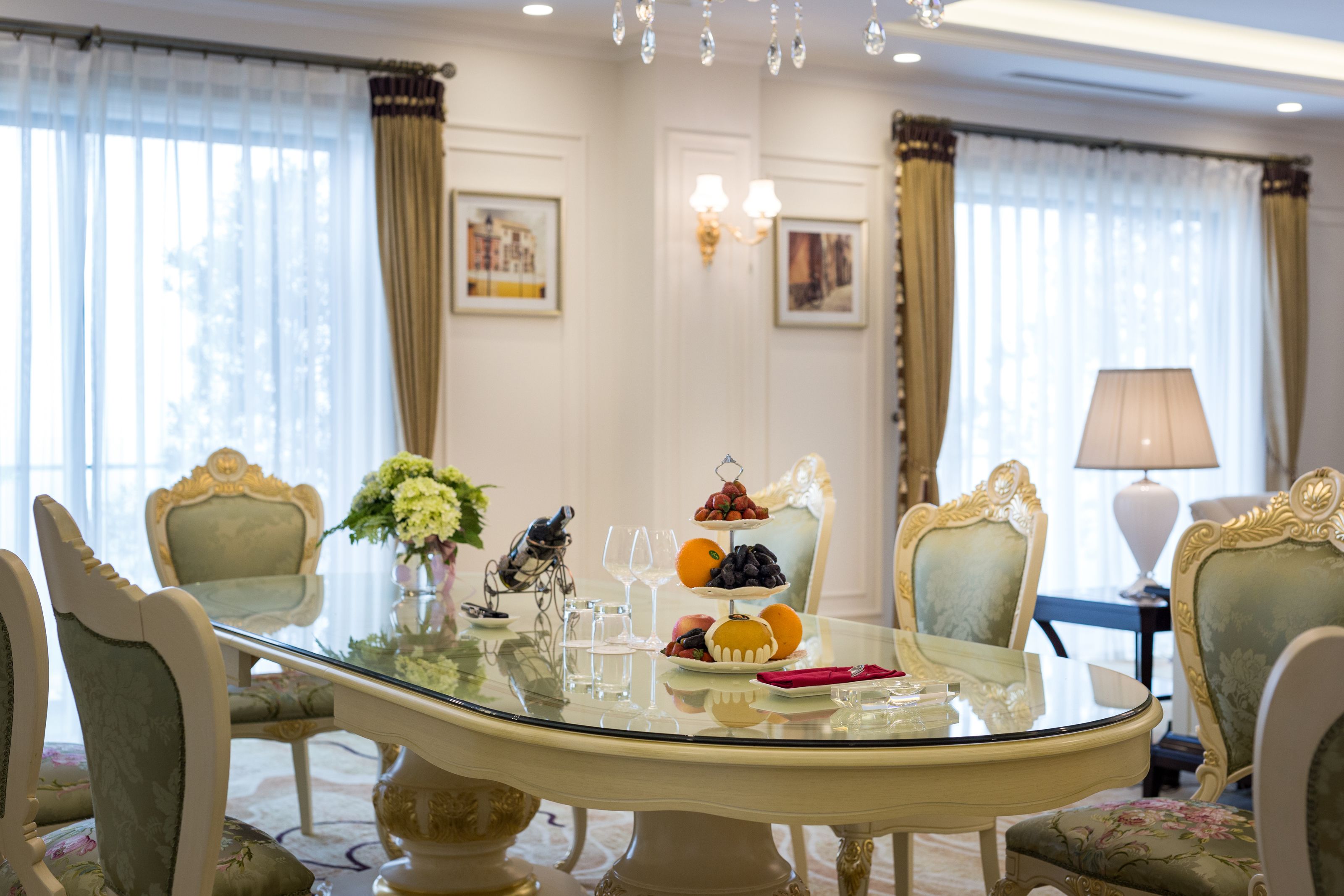 A dining area with a glass table, ornate chairs, and a chandelier.