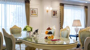 A dining area with a glass table, ornate chairs, and a chandelier.