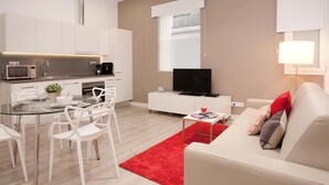 A modern living room with a white sofa, a red rug, and a TV on a white cabinet. - Stylish apartment in city center B1 (Barcelona)
