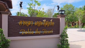 Letrero de Dahla the Resort, con fachada de madera y letras amarillas.
