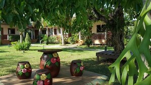 Un patio con un árbol grande, un banco de madera y una mesa con jarrones decorativos.
