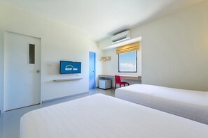A hotel room with two beds, a desk, a chair, a TV, and an air conditioning unit.