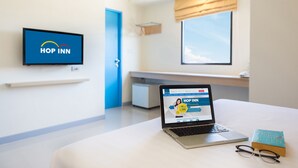 Camera d'albergo con un portatile che mostra un sito web, un libro e un paio di occhiali sul letto.