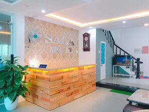 Un comptoir d’accueil avec une pancarte indiquant « SAL MOTEI » et une horloge au-dessus.