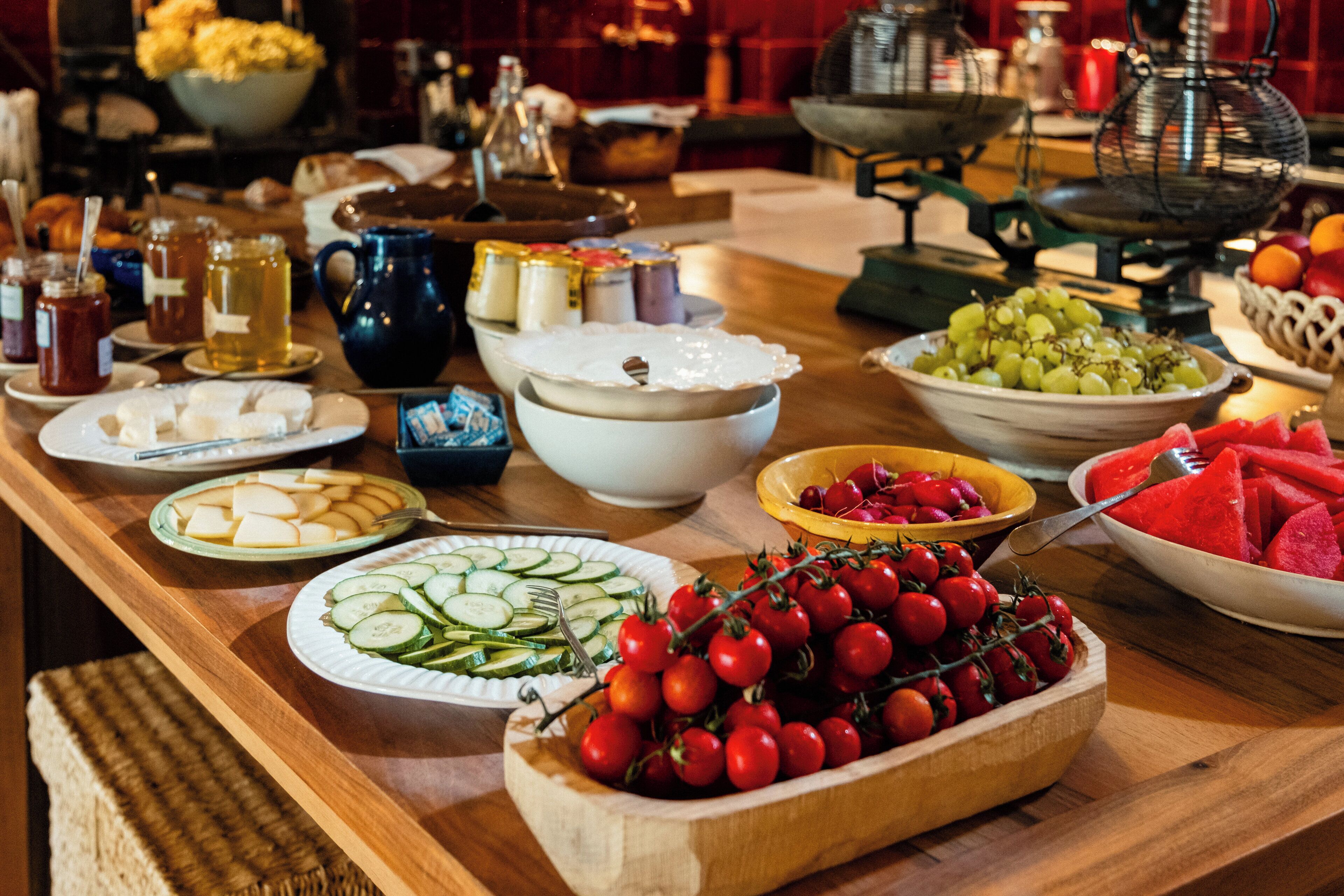A buffet table with various food items including fruits, vegetables, and condiments.