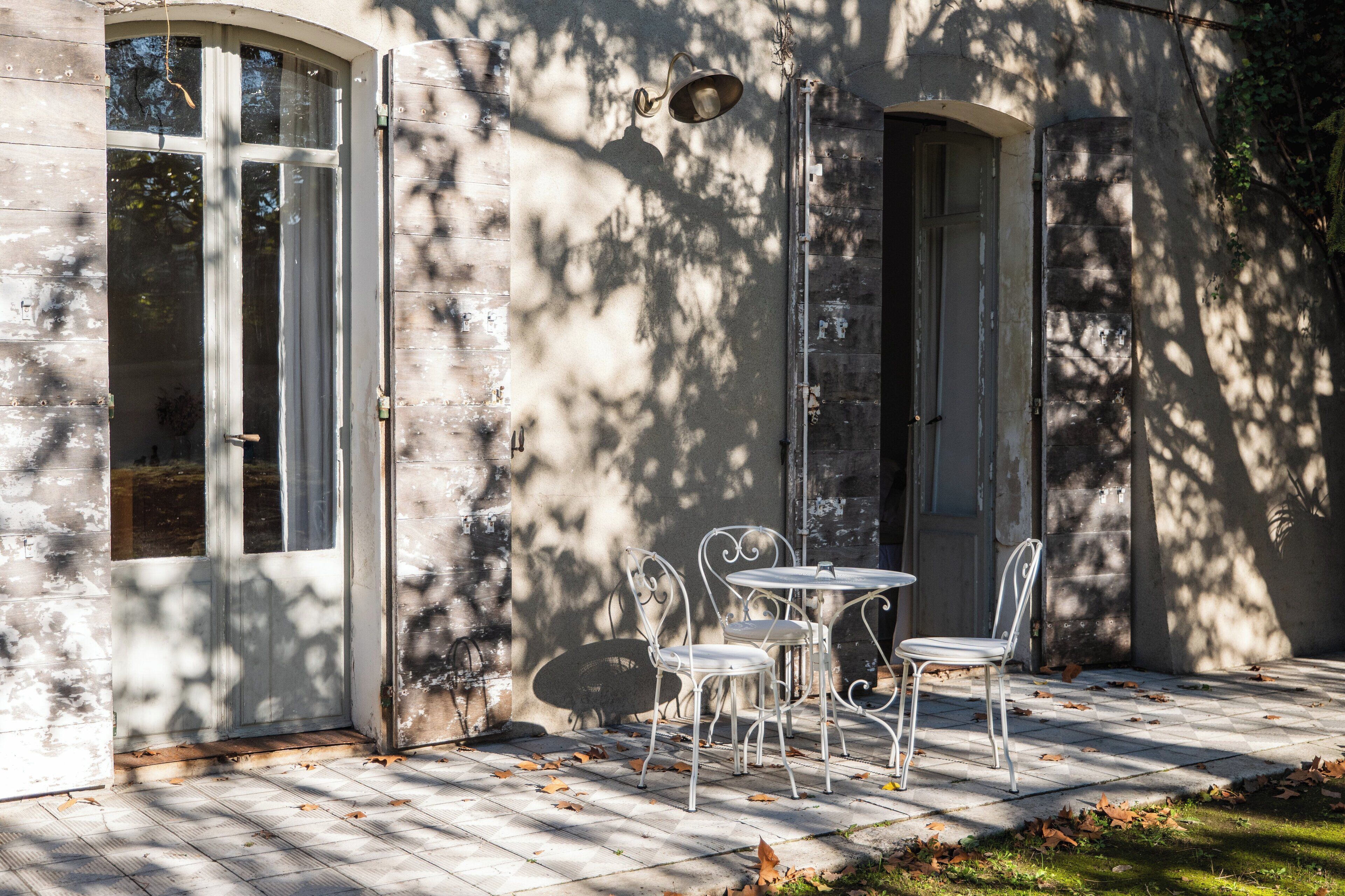 Un patio con una mesa, sillas, un lámpara colgante y una puerta.