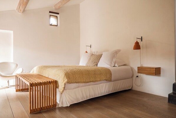 A bedroom with a bed, wooden bench, and a small table. - Le Galinier, Lourmarin, a Beaumier Guesthouse (Lourmarin)