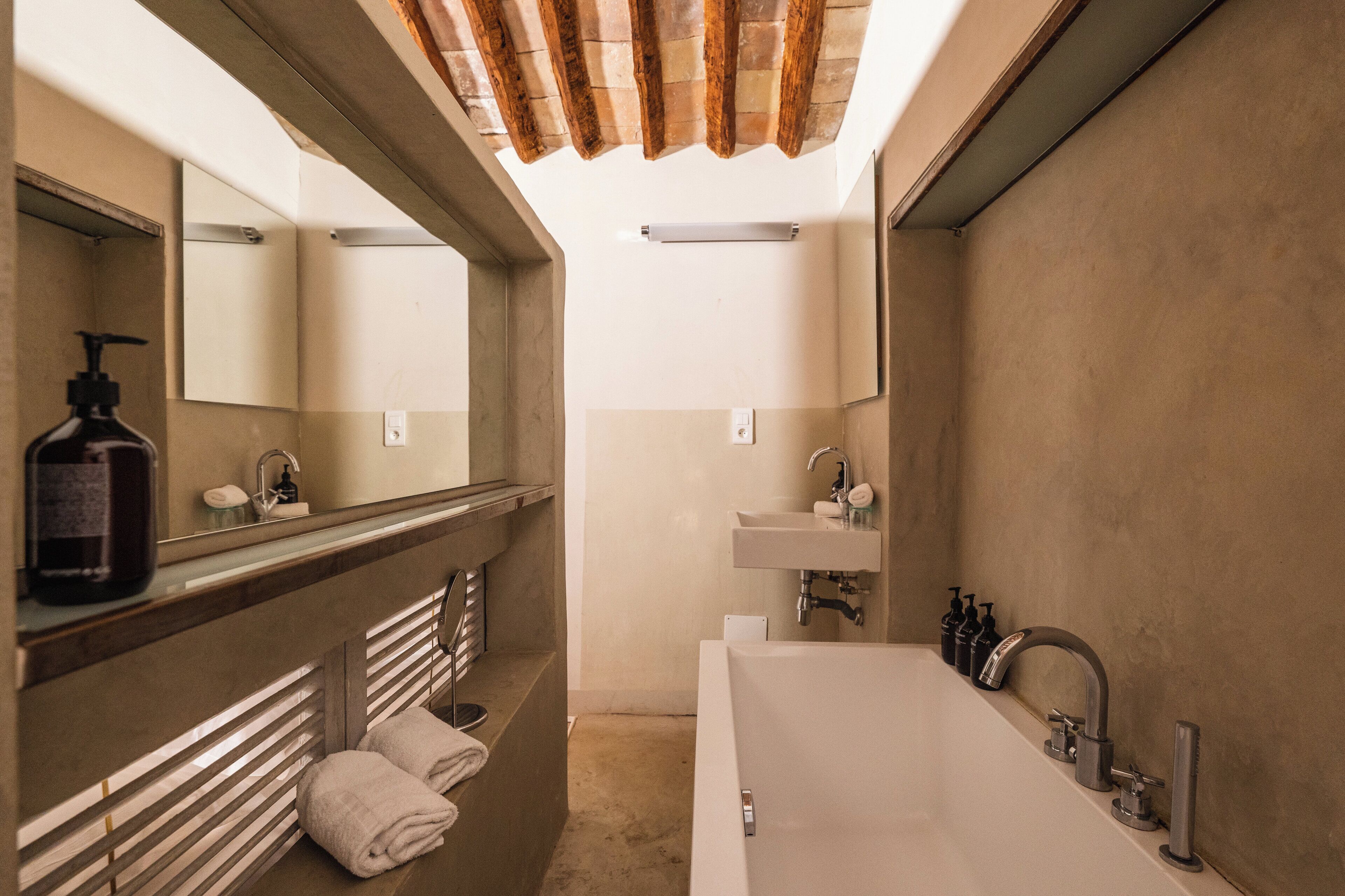 Une salle de bain moderne avec une grande baignoire, un meuble-lavabo avec un miroir et un espace douche.
