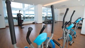 Un gimnasio interior con equipo de ejercicio, ventanas amplias y suelo de madera.