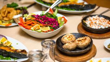 Variedad de platos que incluyen una ensalada, pescado a la parrilla y un recipiente con lo que parece una salsa o aderezo.