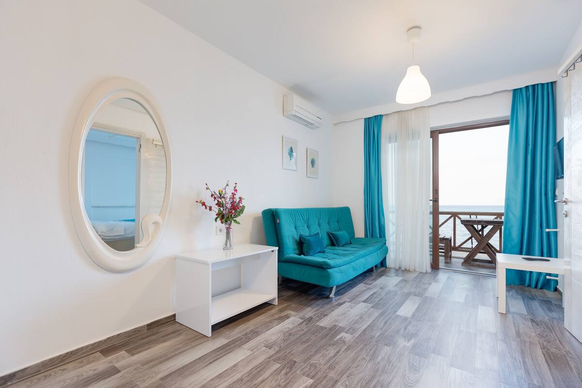 A modern living room with a teal sofa, a white console table, and a large mirror.