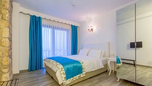 A bedroom with a bed, a nightstand, a mirror, and a window with curtains. - Tasada Otel (Karaburun)