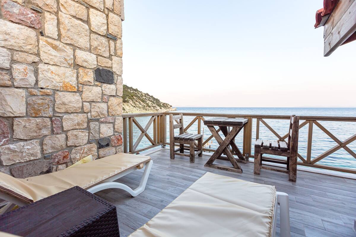A stone wall, wooden deck, and a view of the sea.