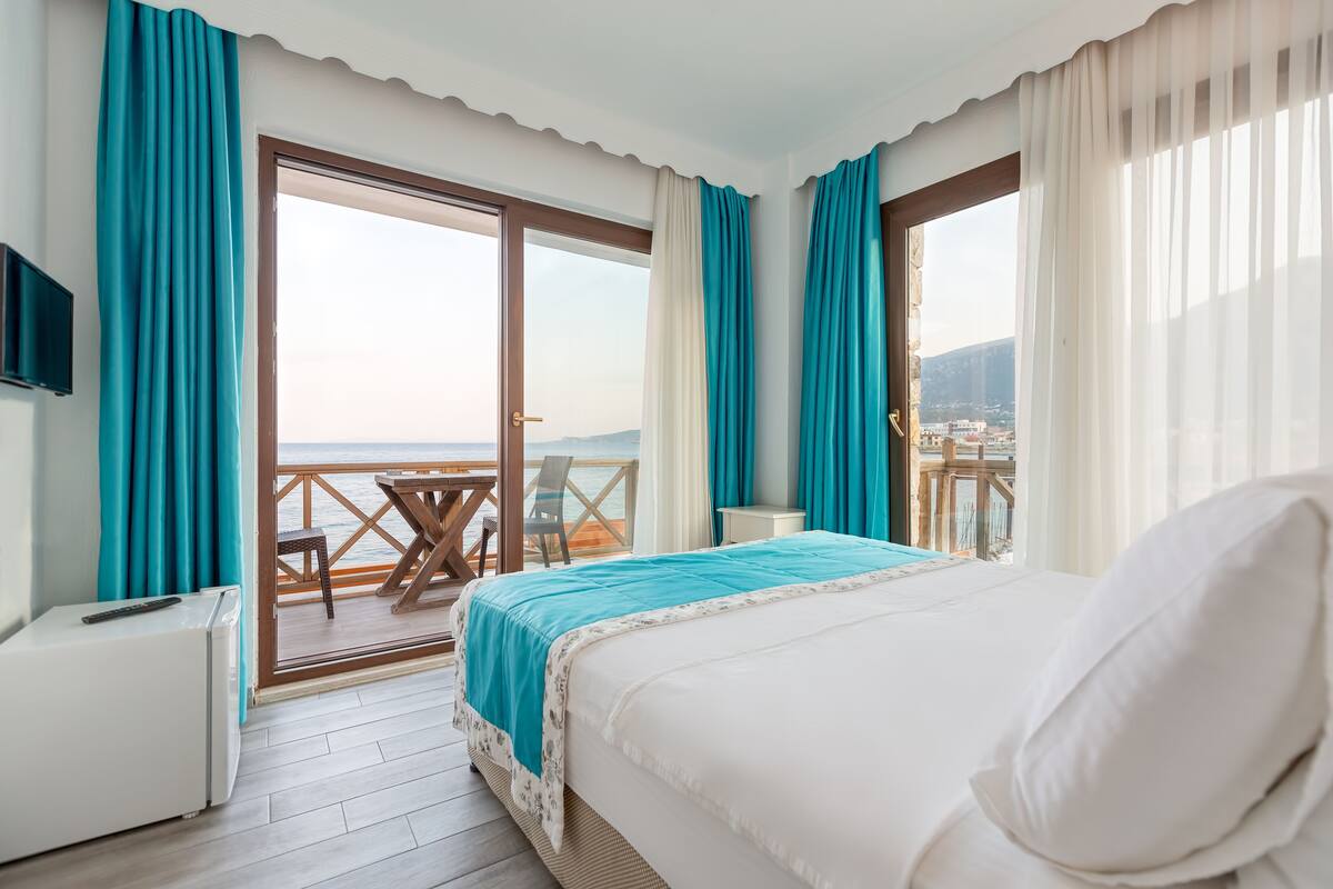 A hotel room with a bed, a desk, and a view of the sea.