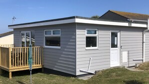 A small, single-story building with a wooden deck, a door, and a window. - A21 Solano, Riviere Towans (Hayle)