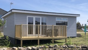 A small, single-story mobile home with a wooden deck and a sliding glass door. - A21 Solano, Riviere Towans (Hayle)