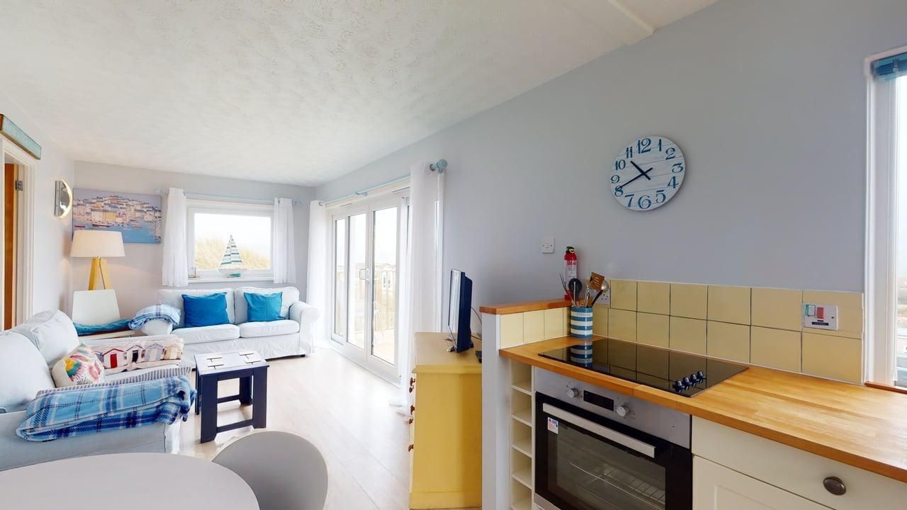 A compact living space with a kitchenette, a dining area, and a sofa with blue cushions.