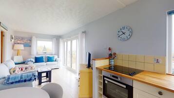 A compact living space with a kitchenette, a dining area, and a sofa with blue cushions.