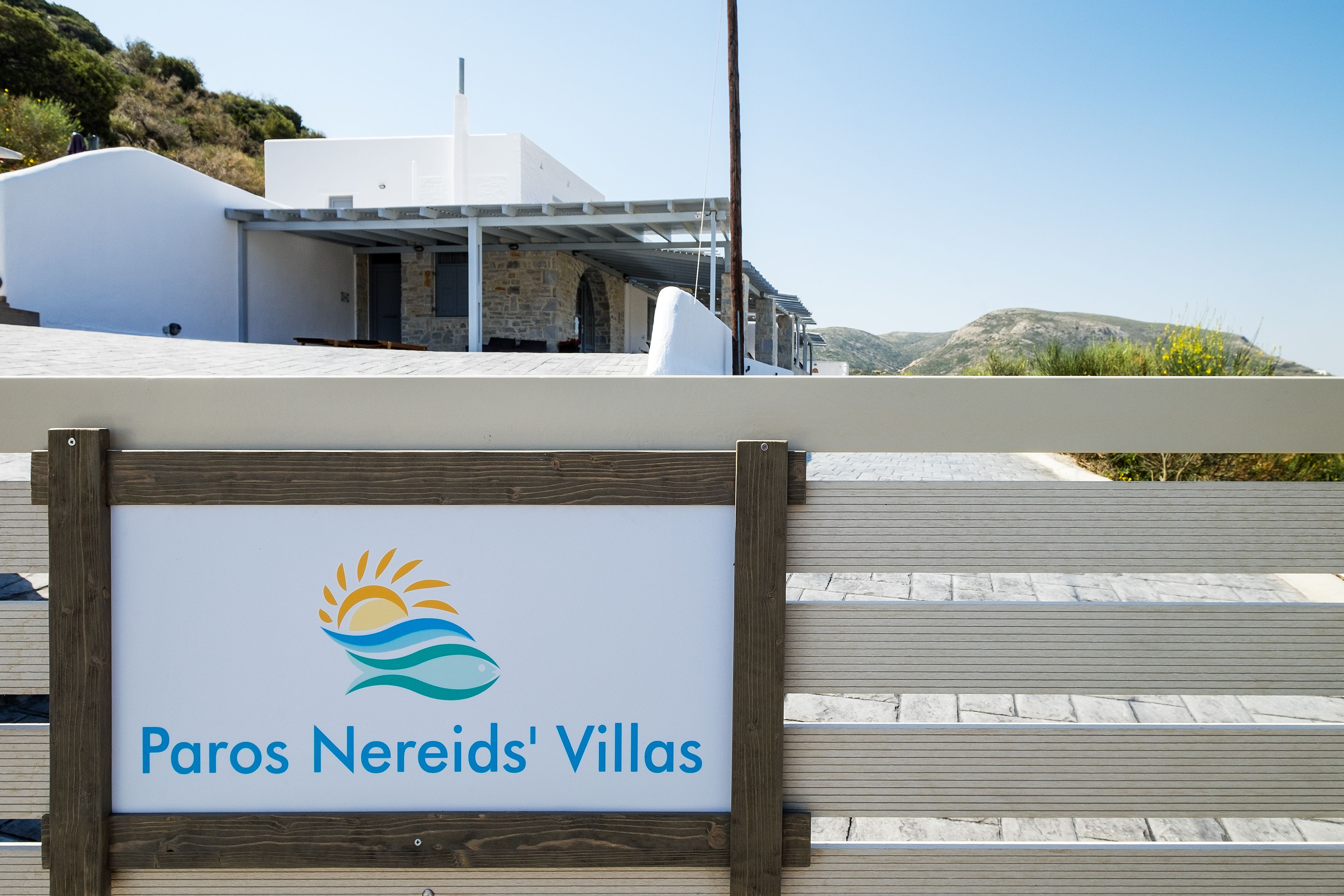 A sign for Paros Nereids' Villas with a logo featuring a sun and waves.
