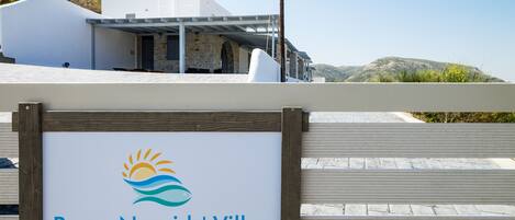 A sign for Paros Nereids' Villas with a logo featuring a sun and waves.