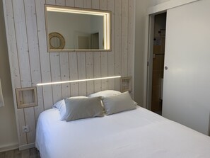 Une chambre à coucher avec un lit, une table de chevet, un miroir et une porte.