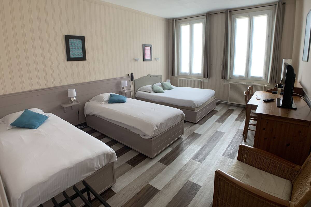 Habitación de hotel con dos camas, un escritorio, una silla, un televisor y una ventana con cortinas.