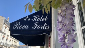 Een hotelschild met de naam 'Hotel Roca Fortis' en een decoratieve luifel.